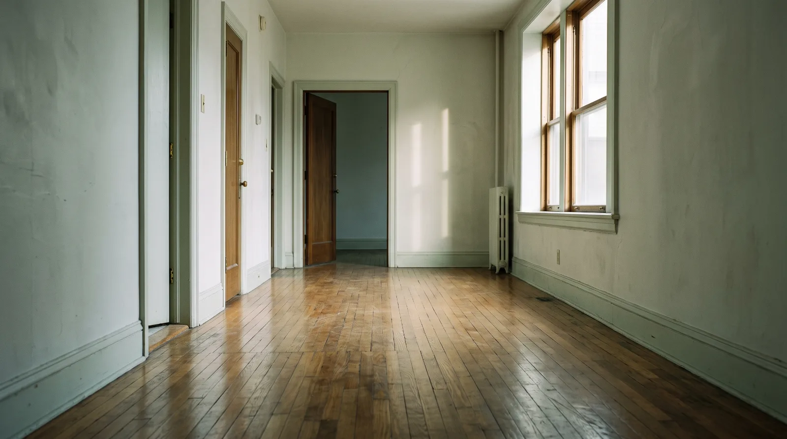 Lichtdurchfluteter leerer Flur mit Parkettboden in einer Wohnung, in der die Nachfolge für ein Haustier offen ist.